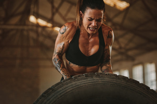 Woman lifting a large tire in a gym setting
