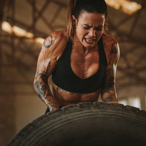 Woman lifting a large tire in a gym setting