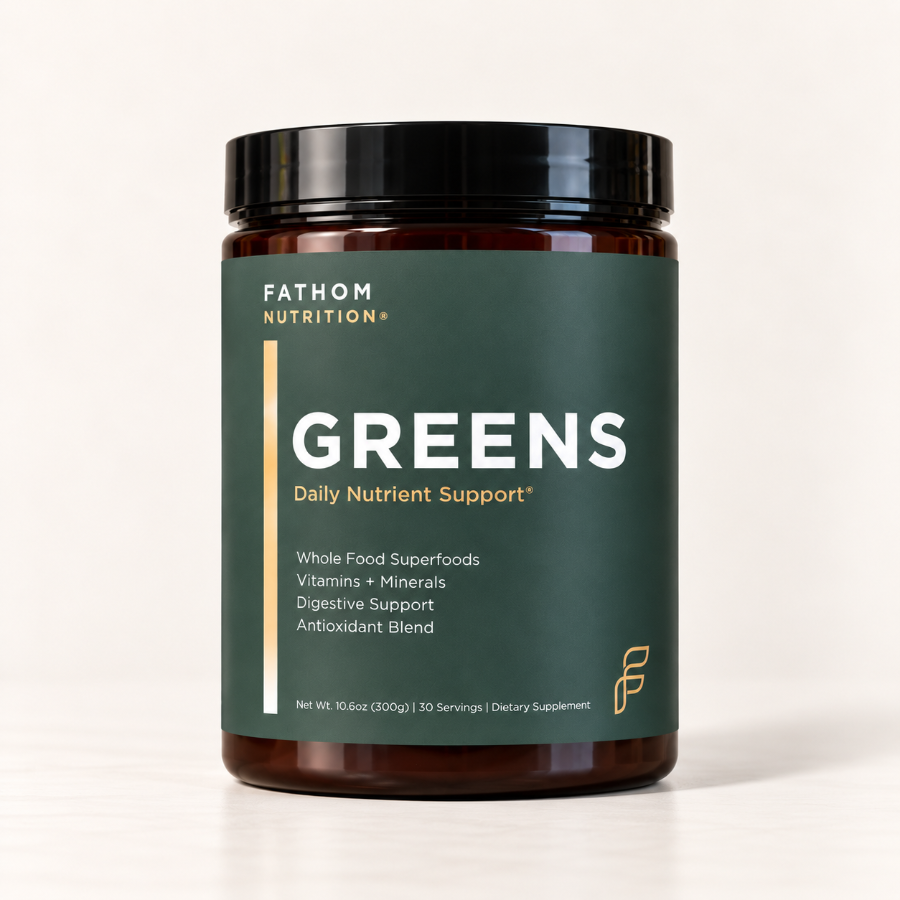 A jar of Fathom Nutrition 'Greens' Daily Nutrient Support dietary supplement, featuring a dark green label and amber brown jar on a light beige background.