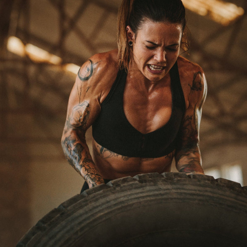 Woman lifting a large tire in a gym setting