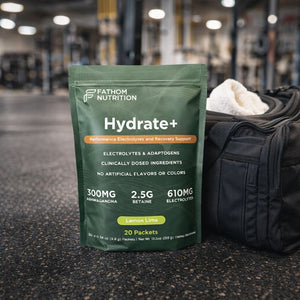 Fathom Nutrition Hydrate+ supplement package on a gym floor with gym equipment in the background