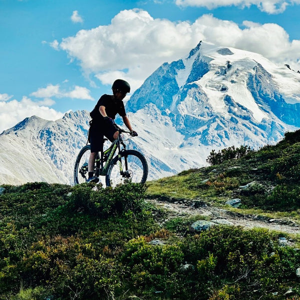 Person on a mountain bike with snow-capped mountains in the background