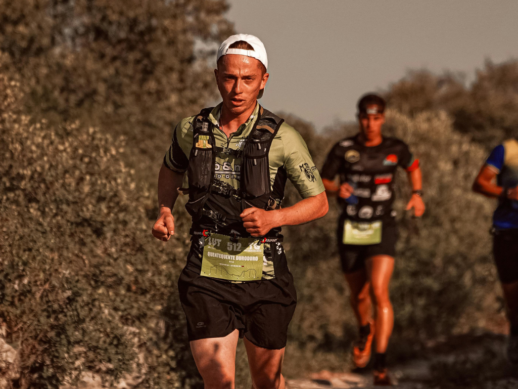 Person running in a desert landscape with a vest and number on bib